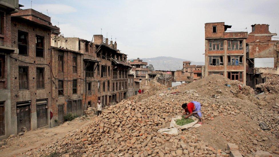 A woman dries vegetables on the rubble of a building damaged in the April 2015 earthquake in Bhaktapur