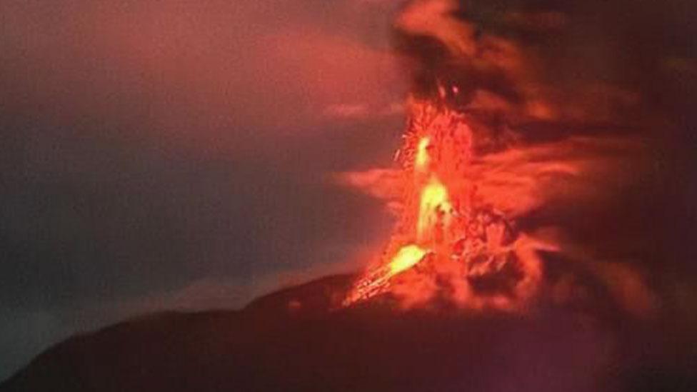 A red flash of lava above the erupting Mount Ruang, an Indonesian volcano