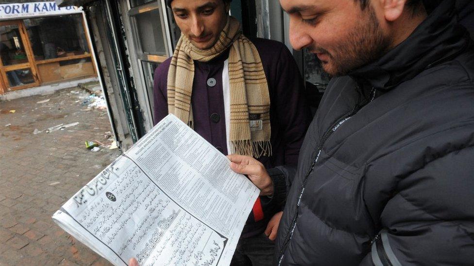 Men reading a newspaper in Srinagar