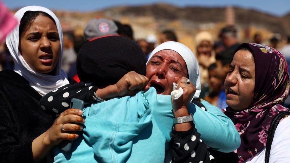 Three mourners cry during a funeral in Moulay Brahim, Morocco