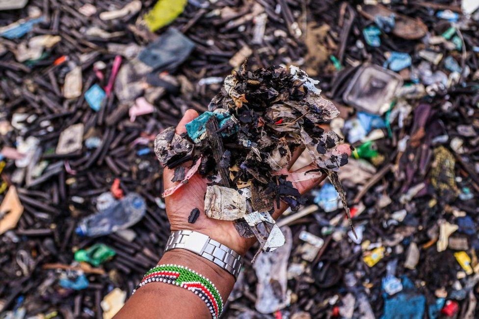 MOMBASA, KENYA - 2022/06/26: A man's hand is holding pieces of plastic trash collected at the shore in Lamu Old Town. Pollution from human activities has negatively impacted the oceans.