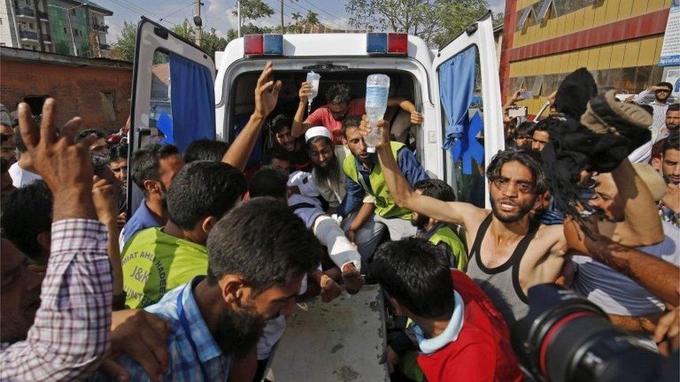 Volunteers carry an injured man from an ambulance outside a hospital who was shot during clashes between security forces and protesters in Srinagar on July 11, 2016.