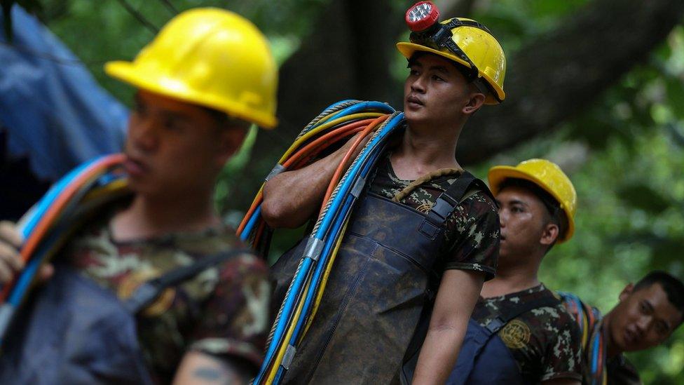 Rescuers carry cables outside the Tham Luang cave complex in Thailand on 5 July 2018