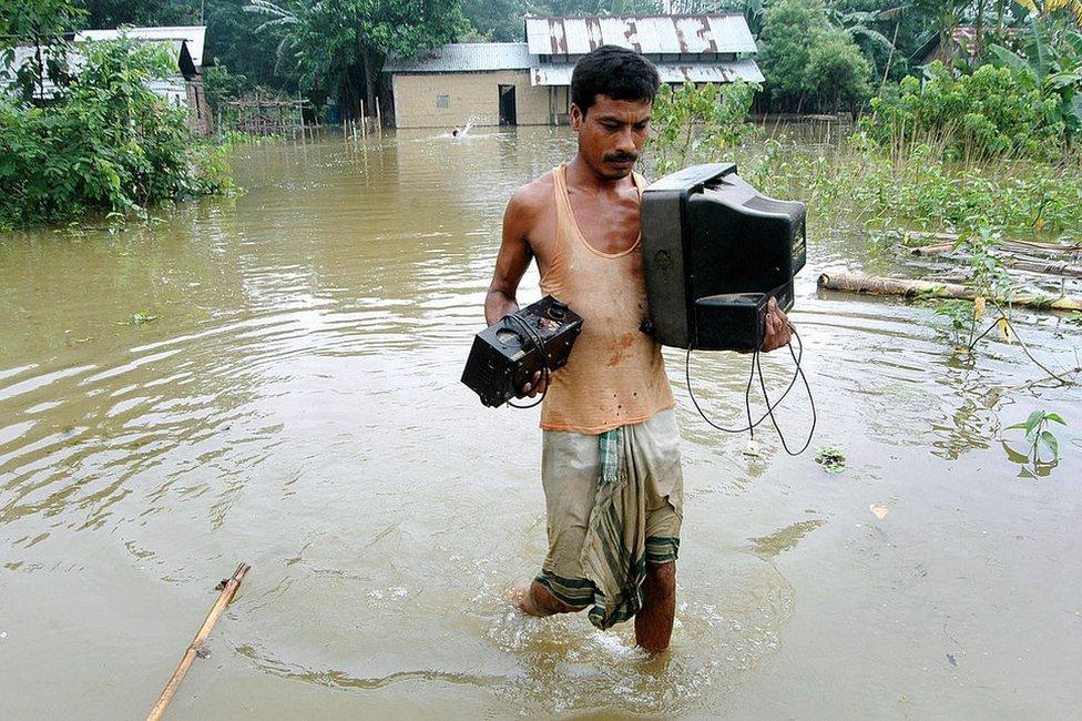 An Indian man carries a television set through flood water in the flood-affected village of Nellie, in the Morigoan district, some 75 km from Guwahati, the capital city of India?s northeastern state of Assam, 10 September 2007.