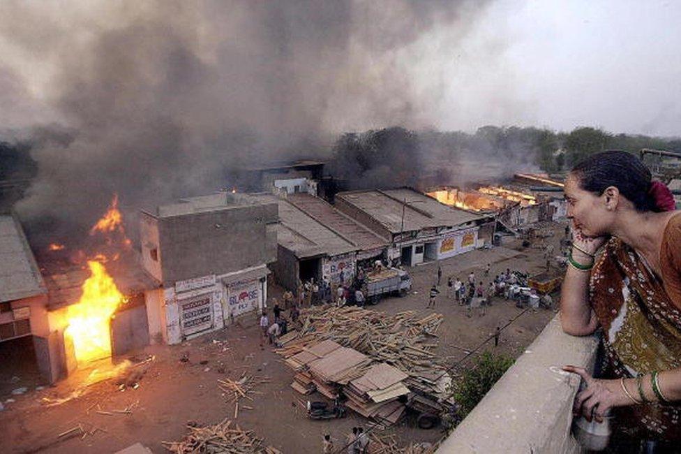 This picture taken 28 February 2002 shows Ahmedabad resident Jaiwantiben watching a wood market burning after it was set ablase by Muslims that fled the Lathi bazar area in Ahmedabad.