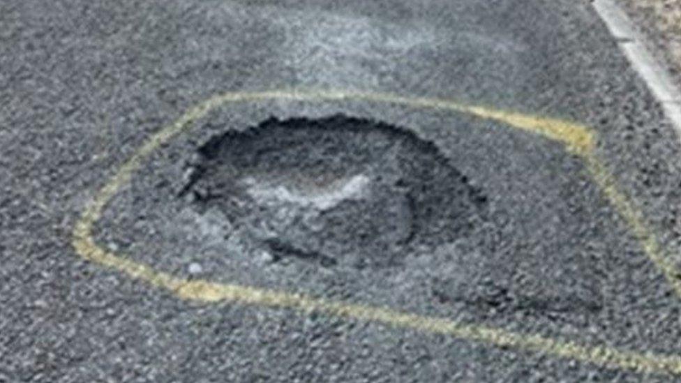 Pothole in the carriageway marked with yellow paint