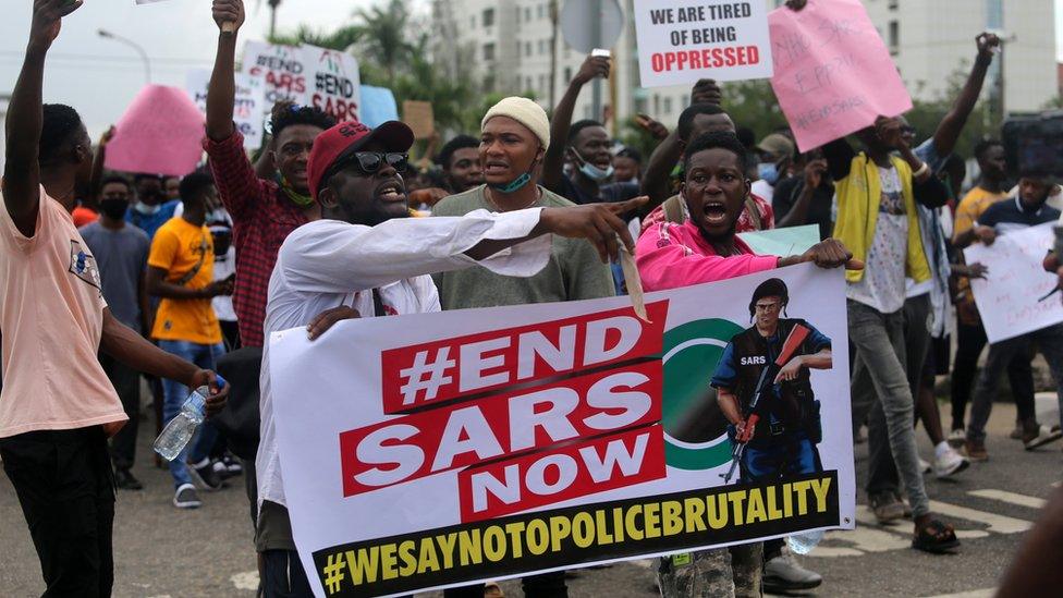 Protesters shout slogans as they hold a banner with the inscription "End SARS now"