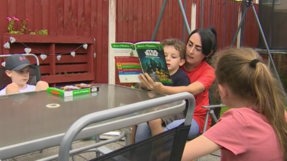 Stephanie Barnett reads to her children in her garden in Connah's Quay, Flintshire, during coronavirus lockdown