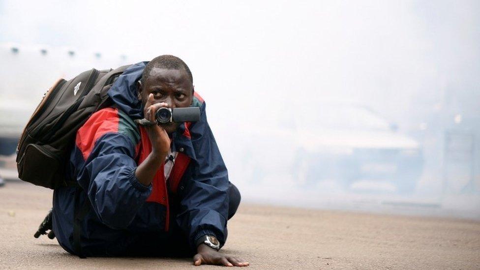 A Ugandan journalist uses his camera after riot policemen fired tear gas to disperse activists led by musician turned politician, Robert Kyagulanyi, during a demonstrating against new taxes including a levy on access to social media platforms in Kampala, Uganda July 11, 2018