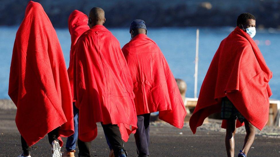 A group of migrants walks to a Red Cross tent to be attended after disembark from a Spanish coast guard vessel in the port of Arguineguin