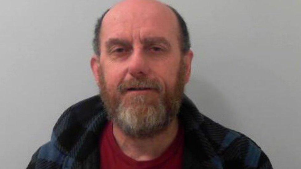 Mark Langford. He is partially bald and has a greying beard. He is wearing a hooded sweatshirt and red top.