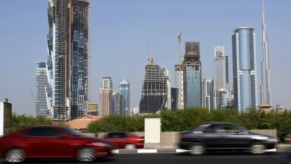 Cars drive past skyscrapers under construction in the Gulf emirate of Dubai on November 27, 2009