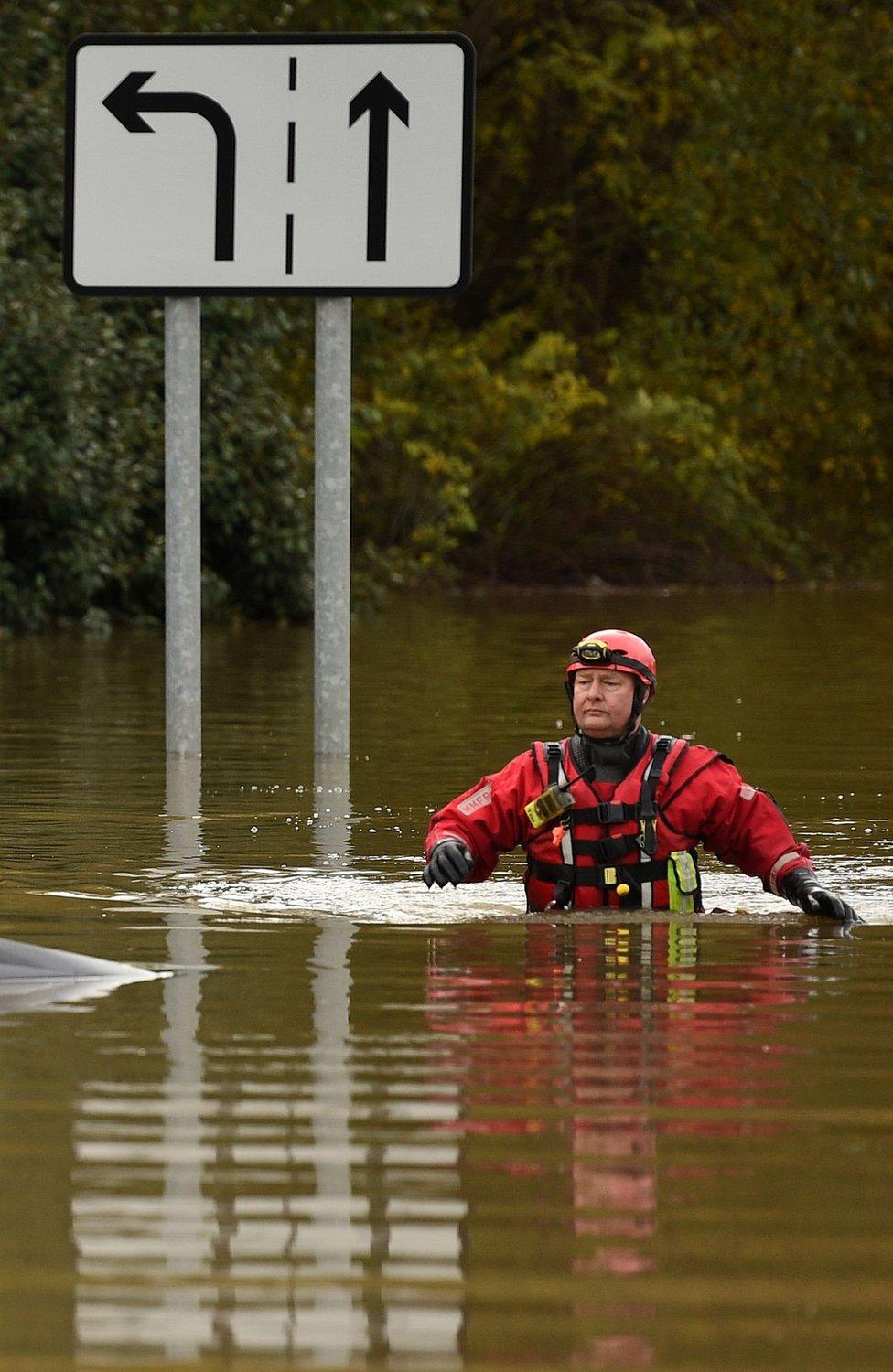 A member of the Fire and Rescue service wades through flood water