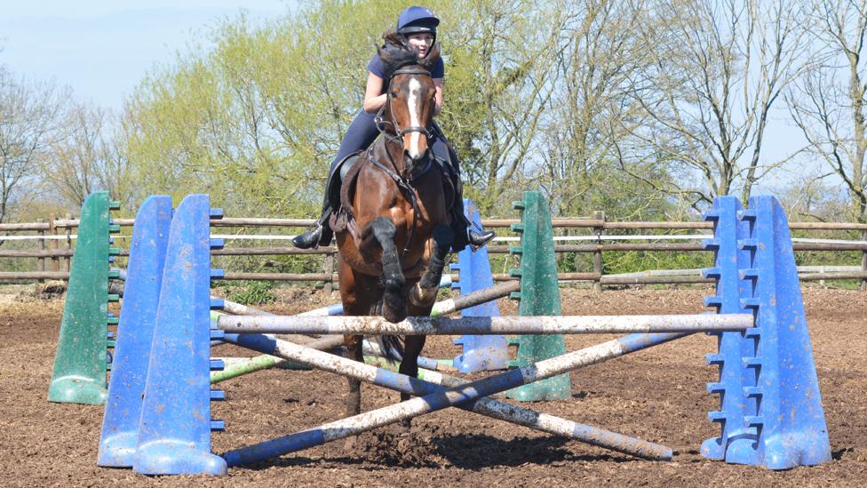 Matilda riding a horse as it goes over some jumps