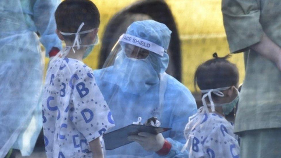 Health workers inspecting young passengers arriving from Wuhan, China, at Kuala Lumpur International Airport