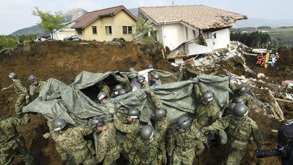 Troops carry a body found under rubble in Minamiaso town (19 April 2016)