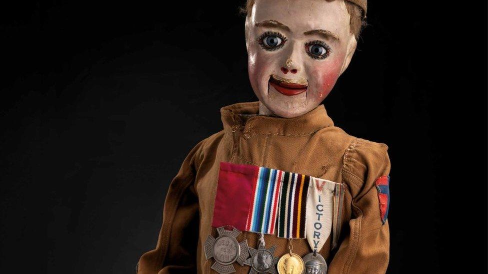 A ventriloquist's dummy in military uniform wearing four medals