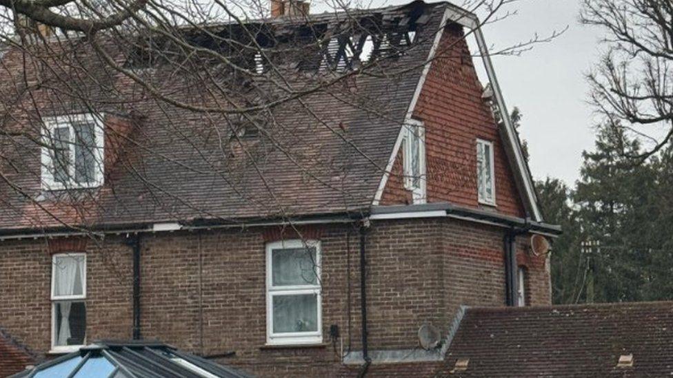 Large brick building in daylight - the roof has been beadly damaged by fire