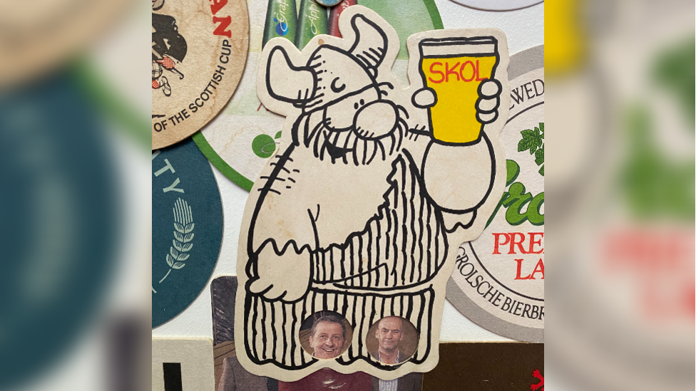 Beer mat depicting comic strip character Hagar the Horrible raising a glass of beer with the test skol typed on it, surrounded by other beer mats not fully visible