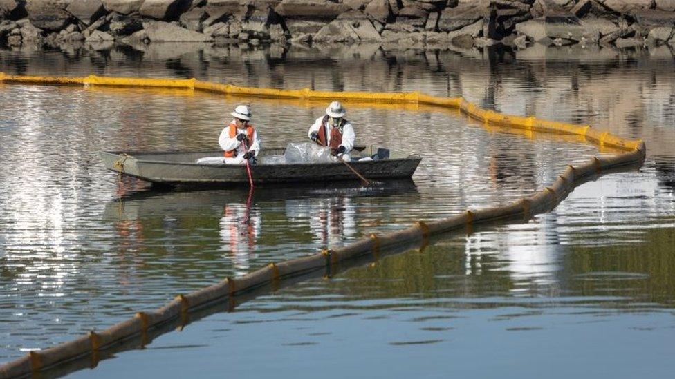 Crews work to prevent further contamination after an oil spill