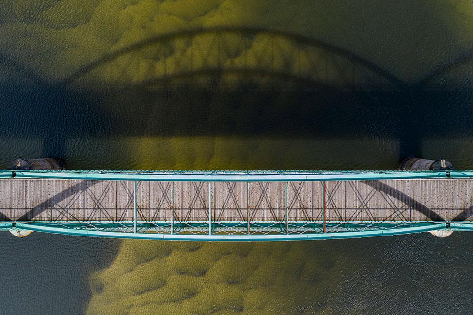 A low sun casts the shadow of a bridge onto water in Alicante, Spain