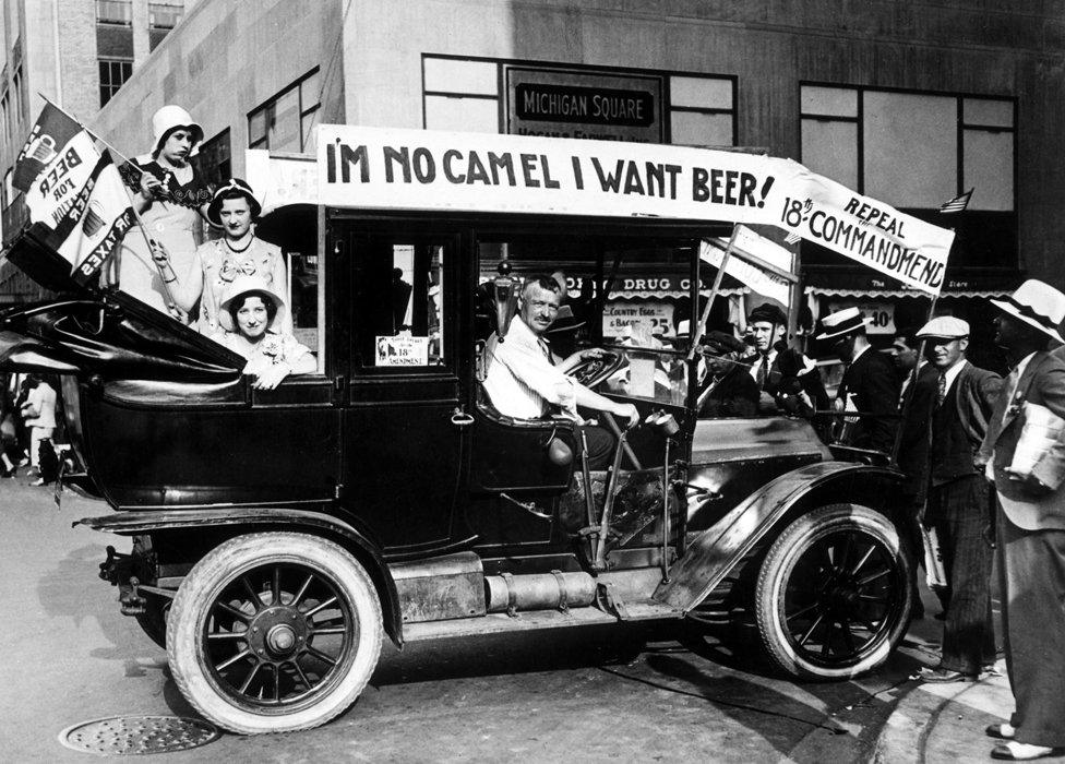 Prohibition protesters parade in a car emblazoned with signs and flags calling for the repeal of the ban