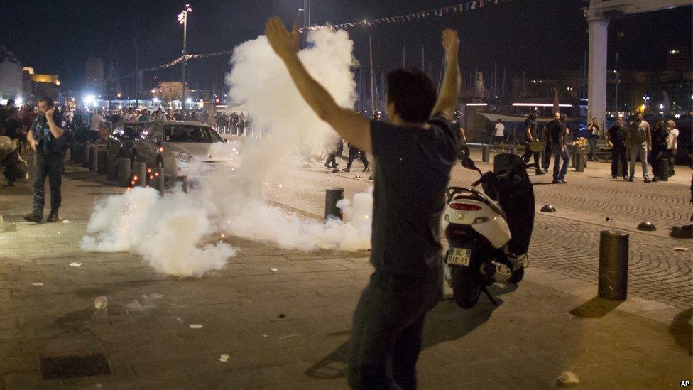 Man with his hands in the air in front of tear gas