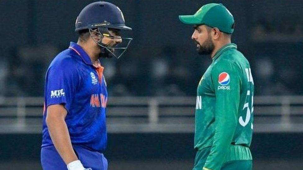 India's Rohit Sharma (L) walks past Pakistan's captain Babar Azam as he arrives to bat during the ICC mens Twenty20 World Cup cricket match between India and Pakistan at the Dubai International Cricket Stadium in Dubai on October 24, 2021.