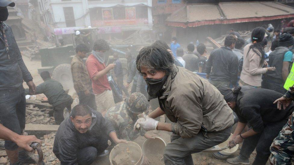 Masked rescuers, surrounded by dust,