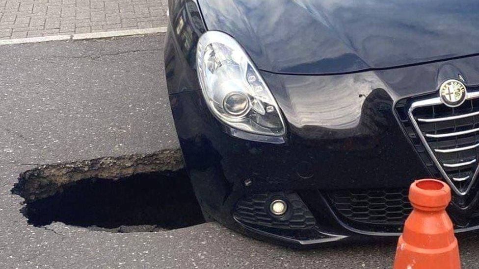 Car with wheel in sinkhole in Witham