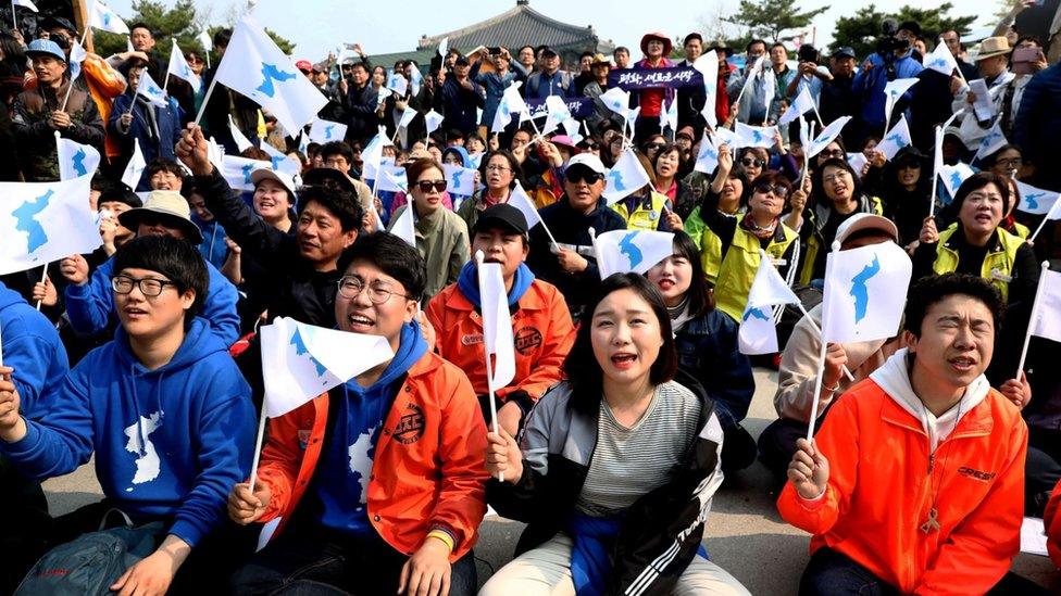 South Koreans react while watching a screen reporting the Inter Korean Summit on 27 April, 2018