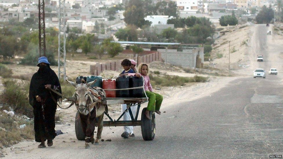 A family uses a donkey to transport water on a road in Sheikh Zuweid, Egypt (24 May 2015)