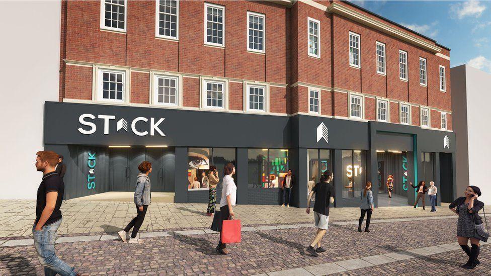 Artist's impression of the Stack development. The ground floor of the three-storey brick venue is painted grey with a white Stack logo above the windows. A number of people, some carrying shopping bags, are walking on the street in front.