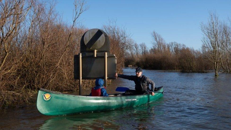 Anthony Gleave and his son Arthur, three, canoe along the flooded A1101 in Welney, Norfolk.