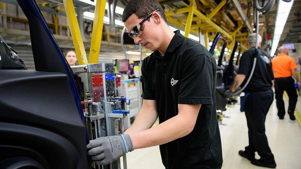 Staff members and technicians work on the Mini assembly line at the factory in Cowley