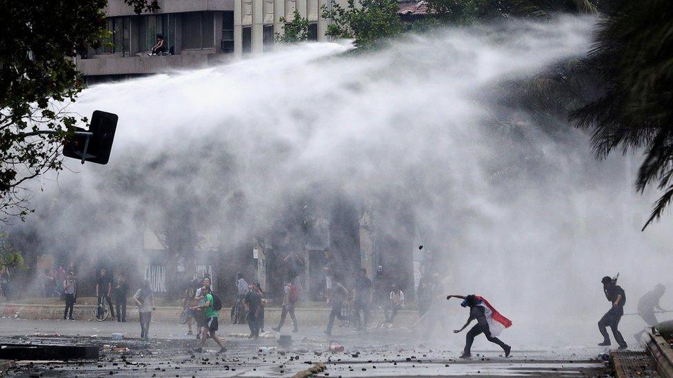 Riot police fire water cannons as they clash with demonstrators during a protest against Chile's state economic model in Santiago