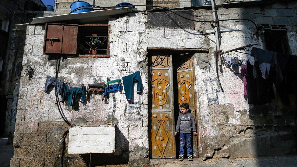 A Palestinian boy stands in the door of a house at the al-Shati refugee camp in Gaza City (28 January 2020)