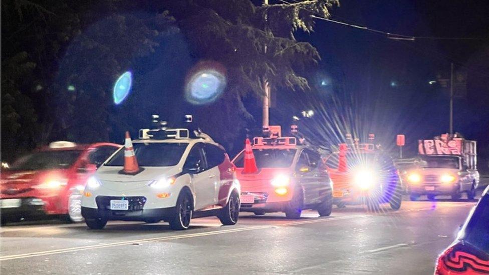 A row of Cruise robotaxis being "coned"