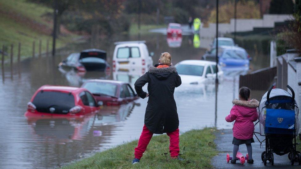 People stop to take a look at cars that have been submerged under nearly a metre of flood water in Bristol. Storm Angus brought hurricane force winds, flooding and power cuts to thousands of homes.