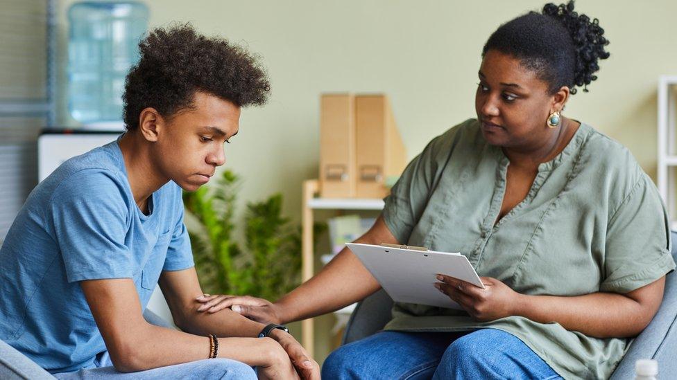 Psychologist working with teenage boy at office (posed by actors)