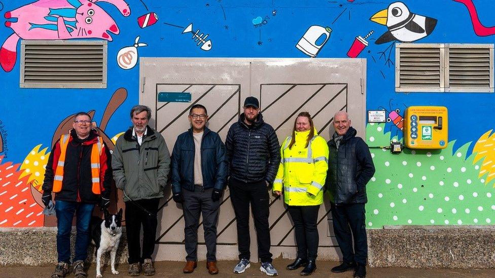 Members of those involved outside united utilities, defibrillator on the wall next to them.