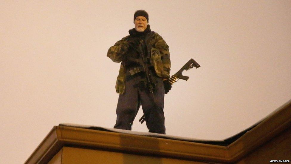 John Karriman. a volunteer from Oath Keepers, stands guard on the rooftop of a business on 26 November 2014 in Ferguson, Missouri.