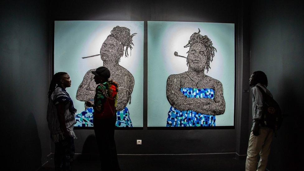 Two painted portraits of a women smoking a pipe.