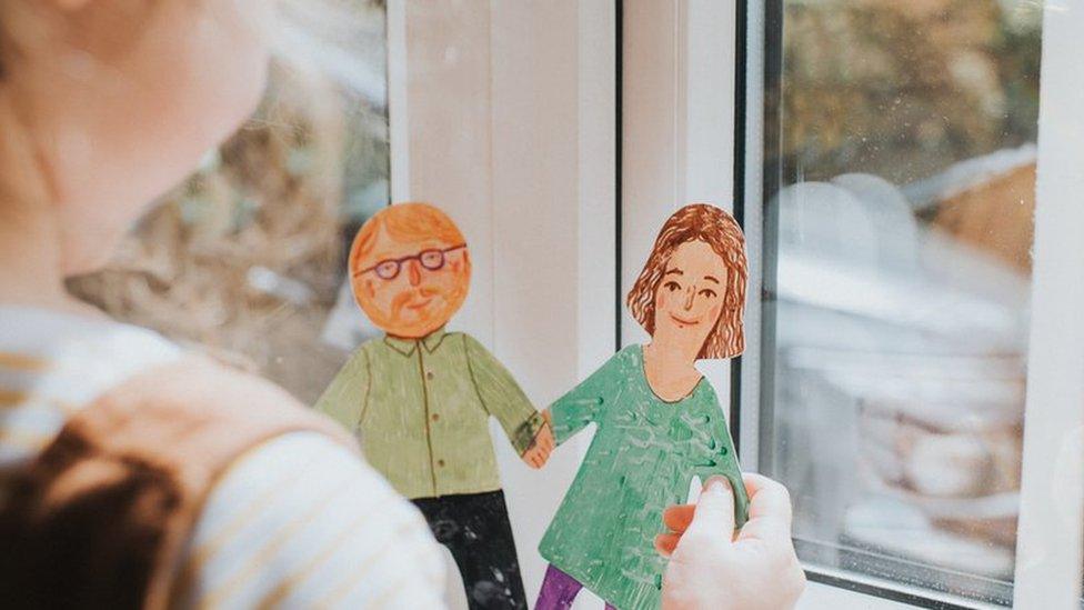 Young girl holding paper dolls of mum and dad