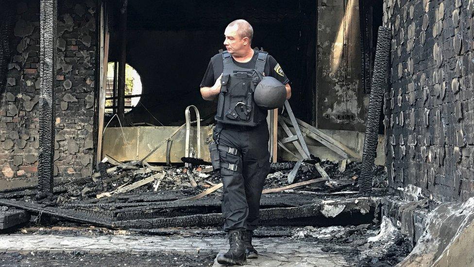 A police officer inspects the site of a burnt house reportedly owned by former Governor of the Ukrainian Central Bank Valeria Gontareva, in Kiev