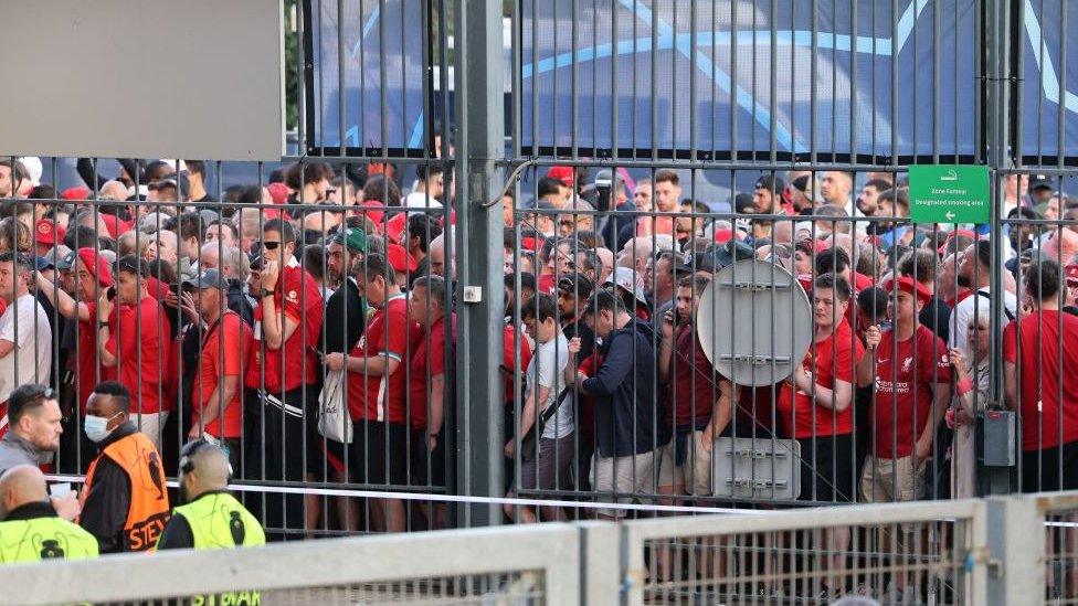 Fans behind a fence.