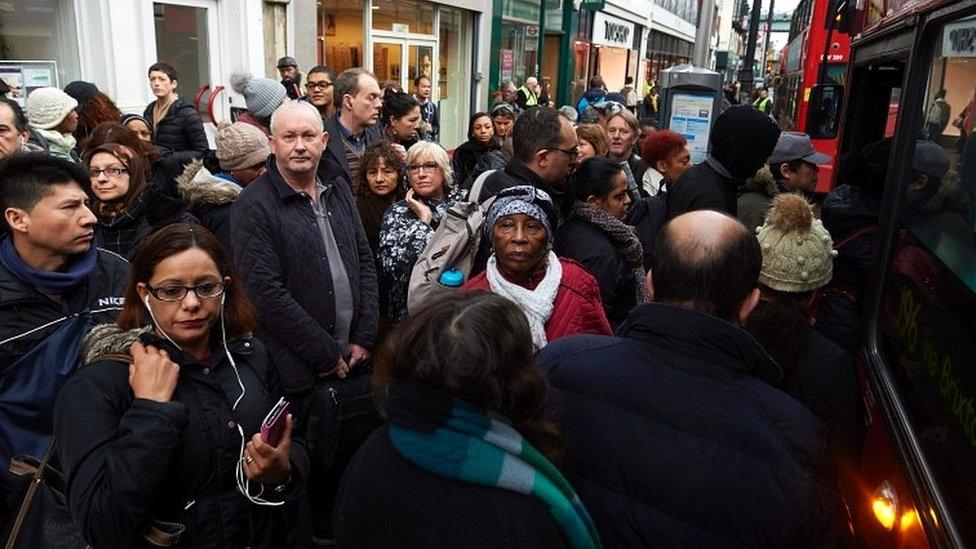 Commuters wait to board buses at bus stops in Brixton