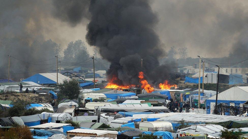 Smoke billows as part of the migrant camp in Calais burns.