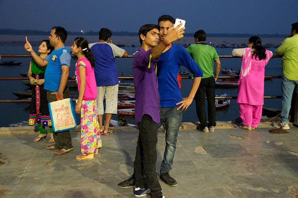 People take photographs with their mobile phones in the evening on the ghats (steps) of the river Ganges in Varanasi