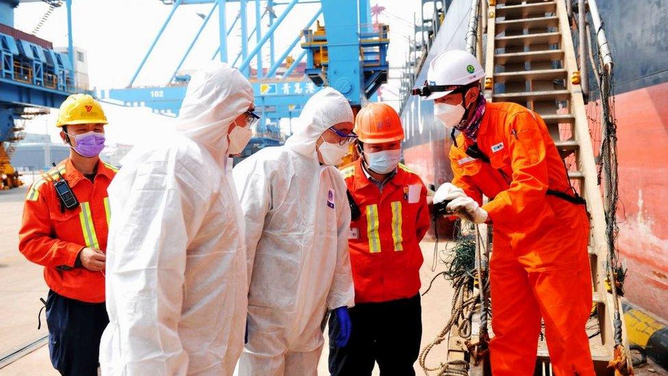 Chinese border guards check a crew member leaving a ship in the container port in Qingdao